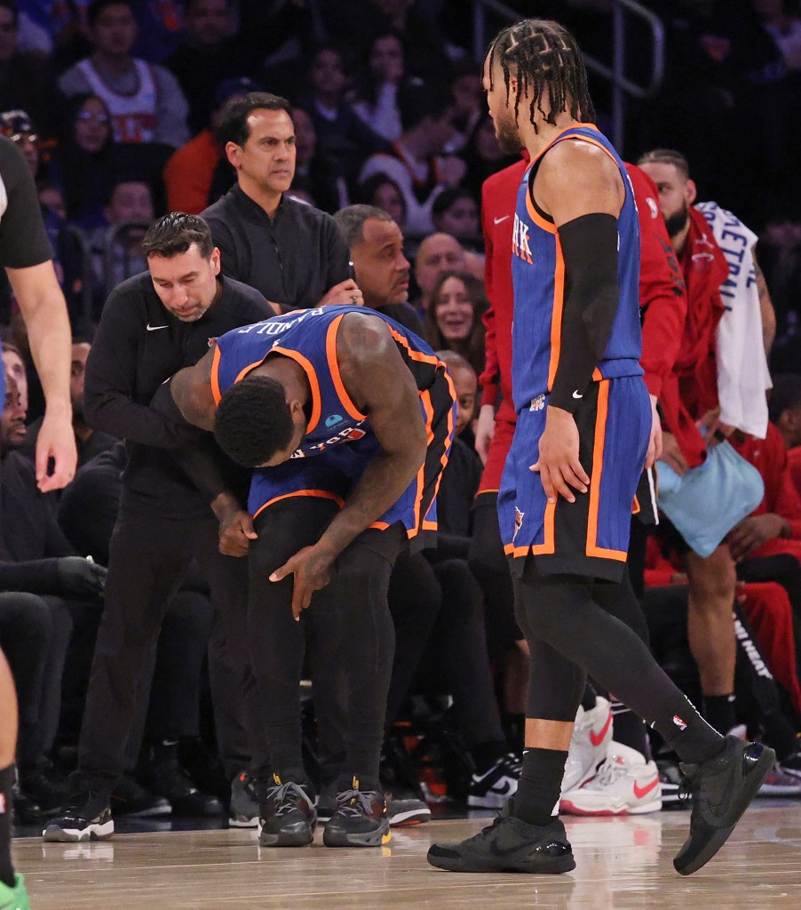 New York Knicks forward Julius Randle (30) receiving help from a trainer after falling over Miami Heat guard Jaime Jaquez Jr. (11) and injuring his shoulder during a basketball game.