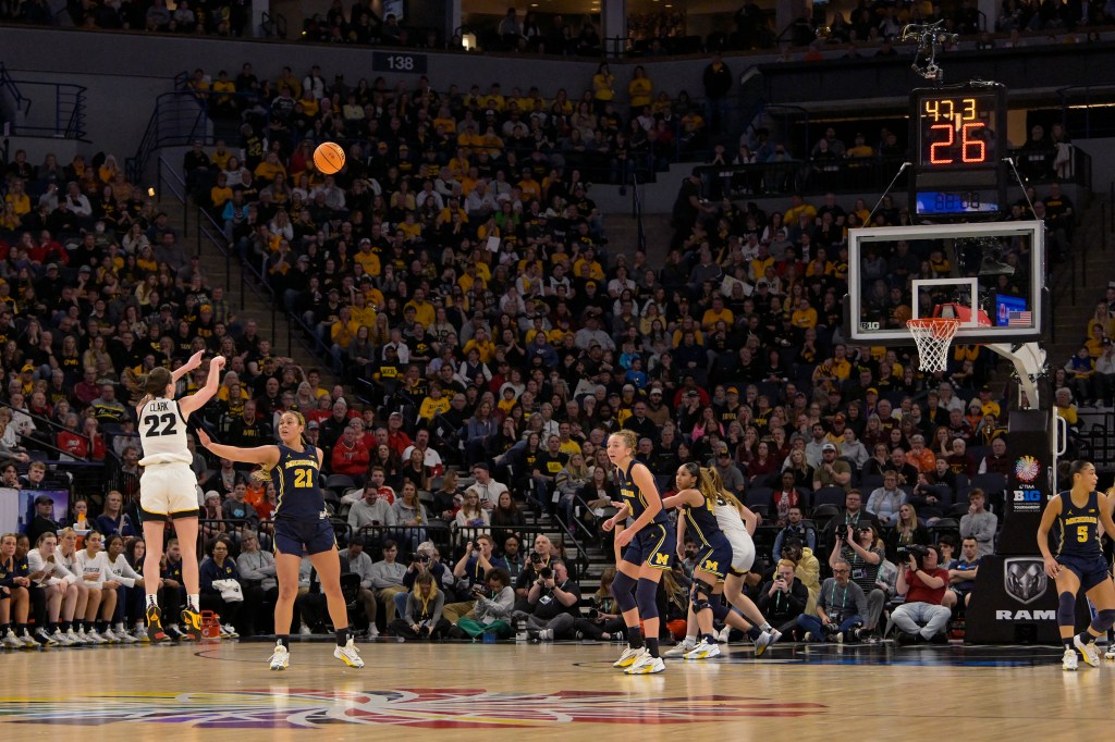 Iowa Hawkeyes guard Caitlin Clark (22) hits a three pointer just inside the half-court line Michigan Wolverines during the first half of a Big Ten Women's Basketball tournament semifinal at Target Center.  