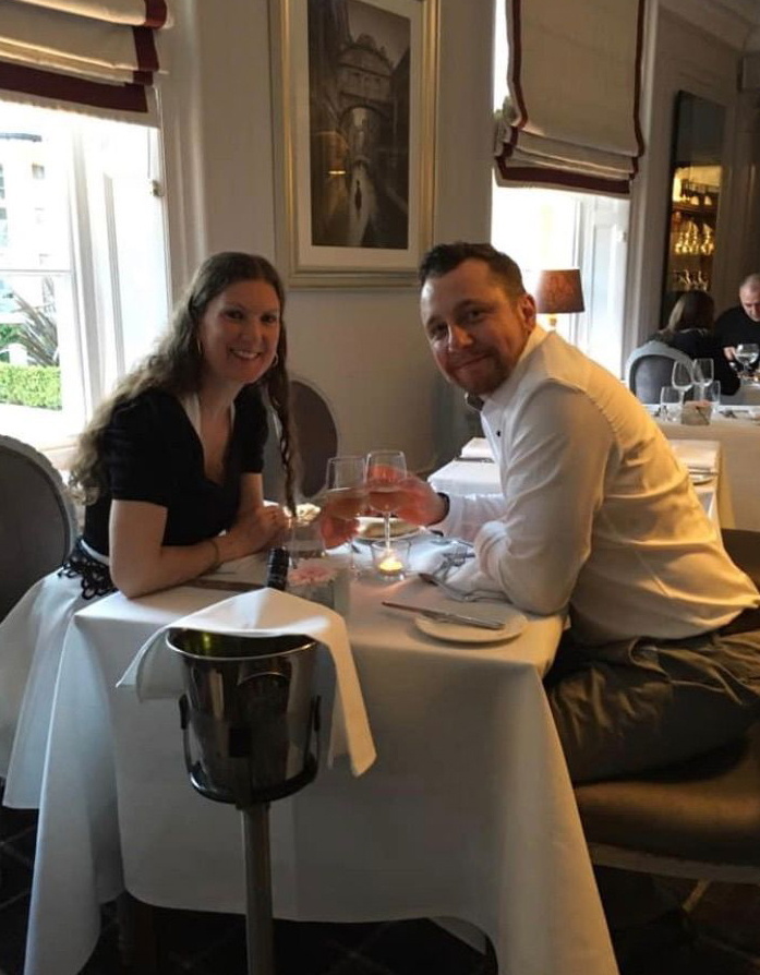 A man and woman, Charlotte and Glen, sitting at a table enjoying a romantic evening together with drinks