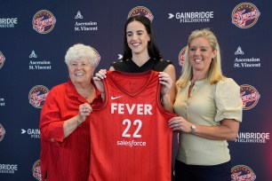 Caitlin Clark of Indiana Fever posing with General Manager Lin Dunn and Head Coach Christie Sides at a WNBA news conference, while holding a jersey.