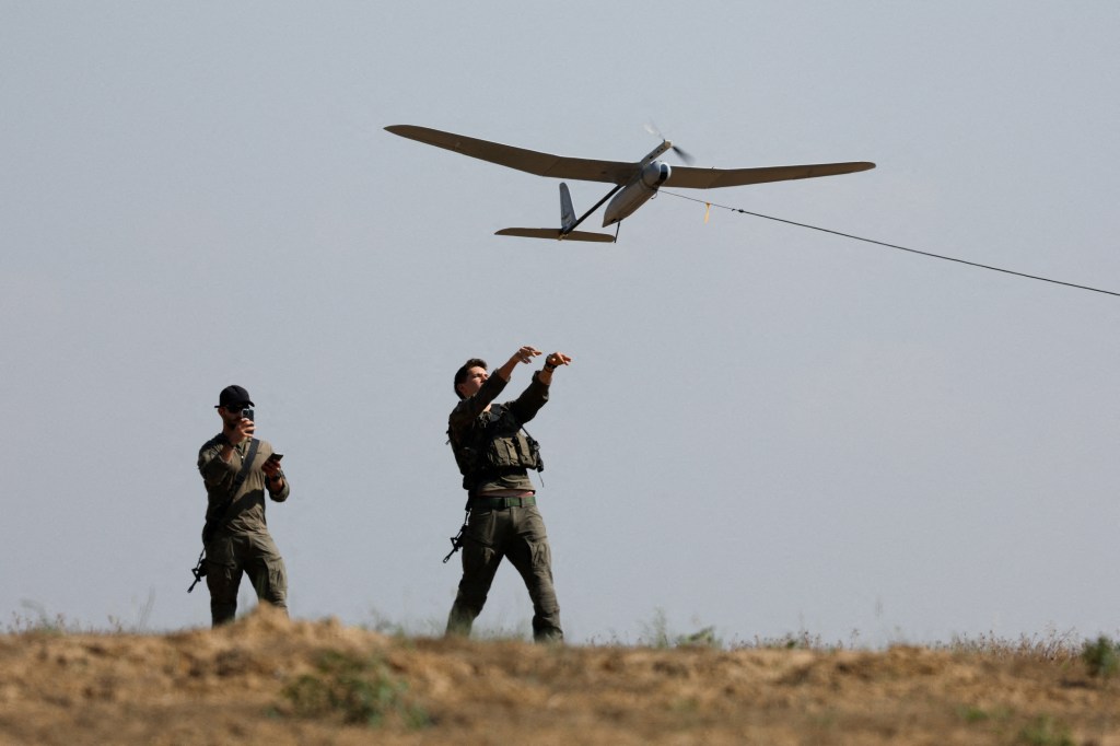 Israeli soldiers in uniform operating a drone near the Israel-Gaza border.