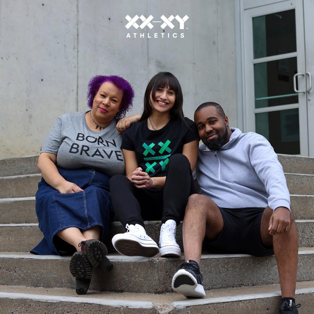 Tabia Lee, in a Born Brave T-shirt, sitting on steps with two other people