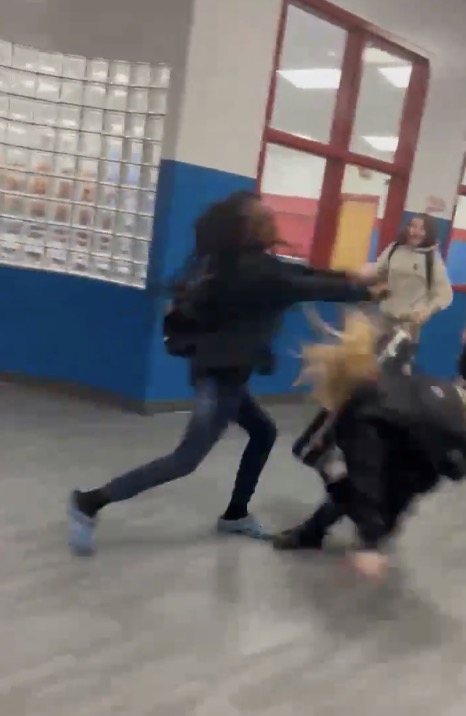 The female student was filmed approaching her unsuspecting victim from behind in the school hallway before shoving her to the ground. 