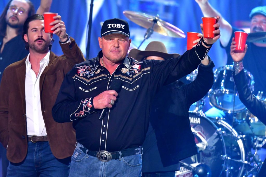 Riley Green and Roger Clemens holding red Solo cups and a microphone on stage at the 2024 CMT Music Awards in Austin, Texas