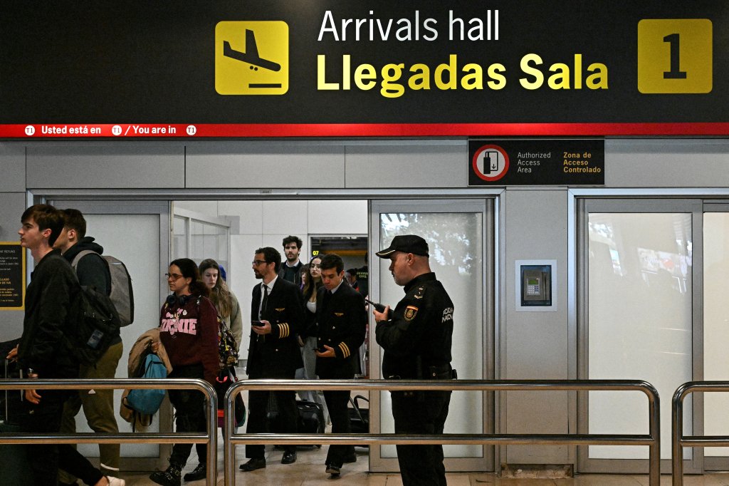 A Spanish national police officer watches as passengers leave the Terminal 1 arrivals hall of the Madrid Barajas airport, on April 3, 2024. Former president of the Spanish Football Federation (RFEF), Luis Rubiales, who landed at Madrid airport in a plane from the Dominican Republic, was detained on his return to Spain today by the Guardia Civil, which is investigating alleged irregular contracts during his term in office, Spanish media report. 