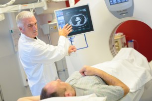 Man on an exam table looking at a screen with his doctor