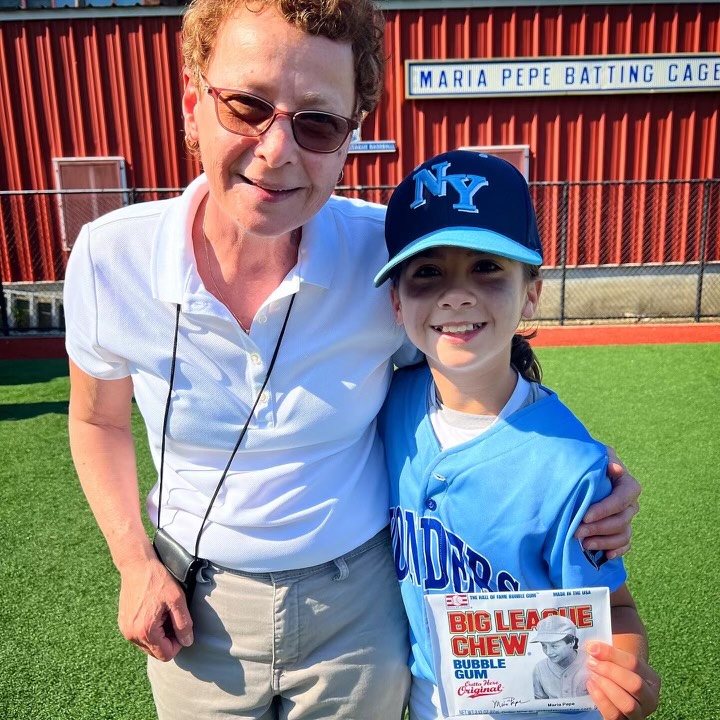 
Maria Pepe standing with a young girl in a baseball uniform