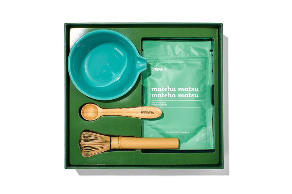 A green box with a matcha tea kit including a bowl and a wooden spoon