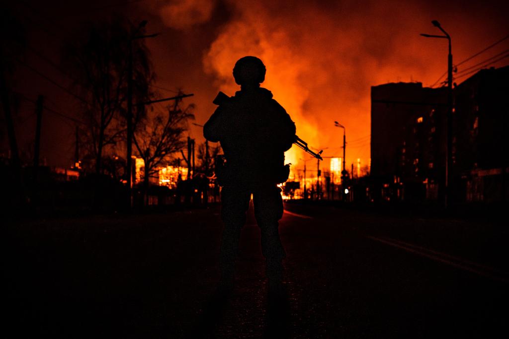 The silhouette of a Ukrainian special forces member is seen in front of a burning gas station after a Russian attack on the city of Kharkiv on March 30, 2022. 