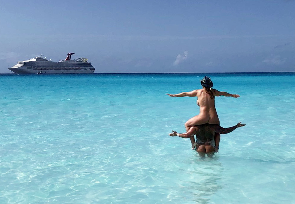 Michael and Laurie Brown, a couple in their fifties, enjoying a naked cruise with the woman sitting on the man's shoulders in the water