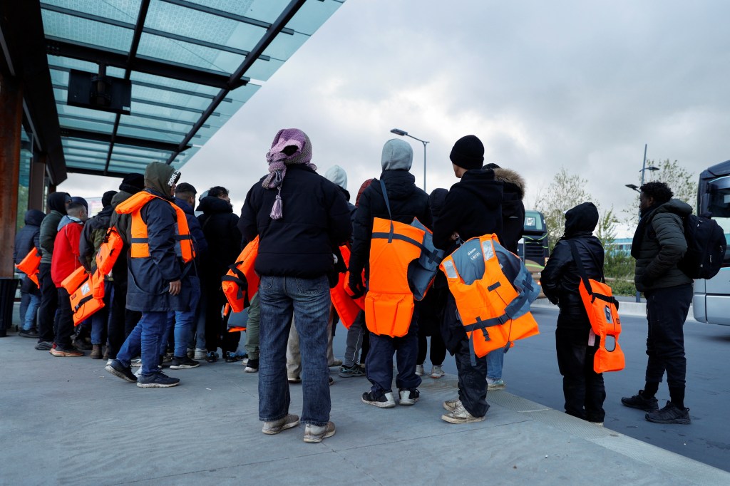 Migrants wait for a bus to return from the beach to their camp, at Calais train station, in Calais, after migrants died in an attempt to cross the English Channel, in France, April 23, 2024.