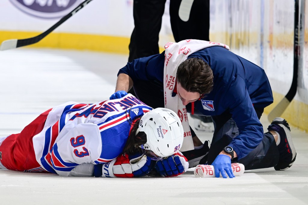 Mika Zibanejad of the New York Rangers is tended to by the trainer during the third period against the New York Islanders at UBS Arena on Tuesday.