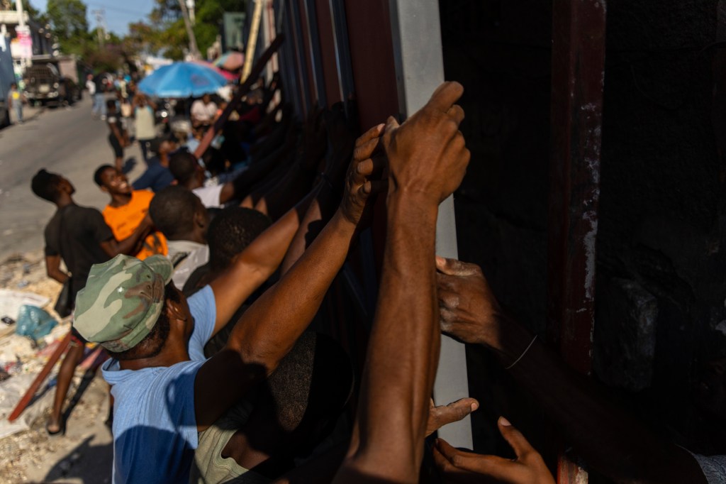 Neighbors raising a metal gate to install as a barricade against gangs in the Petion-Ville neighborhood of Port-au-Prince, Haiti