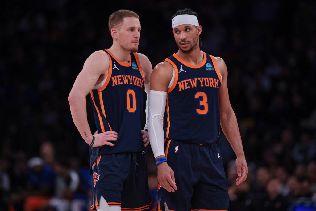 New York Knicks guards Donte DiVincenzo and Josh Hart discussing strategy during a game against the Brooklyn Nets at Madison Square Garden.