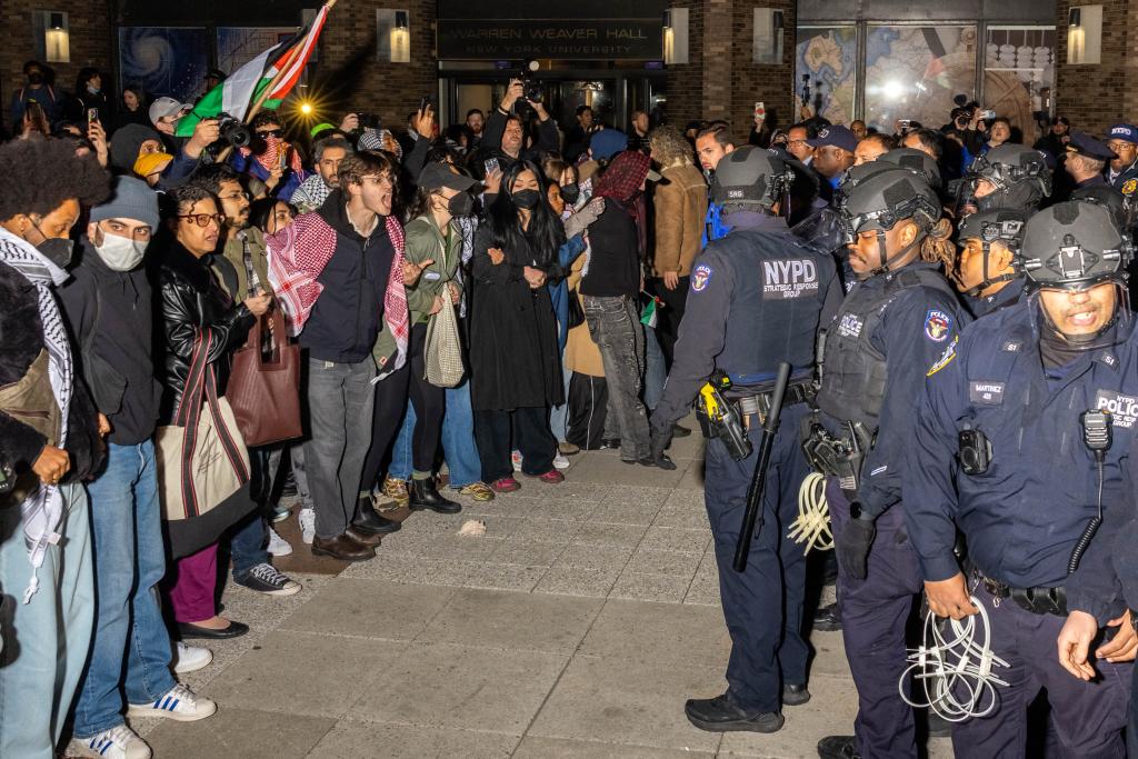 NYPD officers face protesters after detaining demonstrators and clearing an encampment set up by pro-Palestinian students and protesters on NYU's campus.