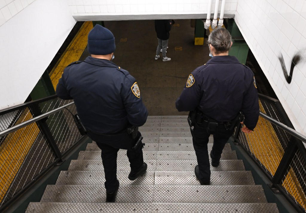 two NYPD officers walking down the stairs at an NYC subway station