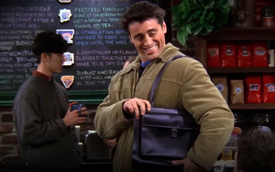 Matt LeBlanc as Joey holding a black leather shoulder bag in Friends Season 5, Episode 13