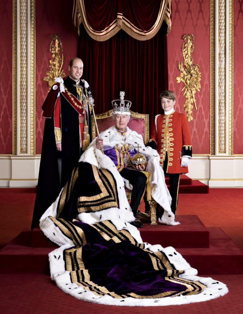 King Charles III, Prince William, and Prince George in full coronation regalia in the Throne Room at Buckingham Palace, with the King holding the Sovereign's Orb and Sceptre.