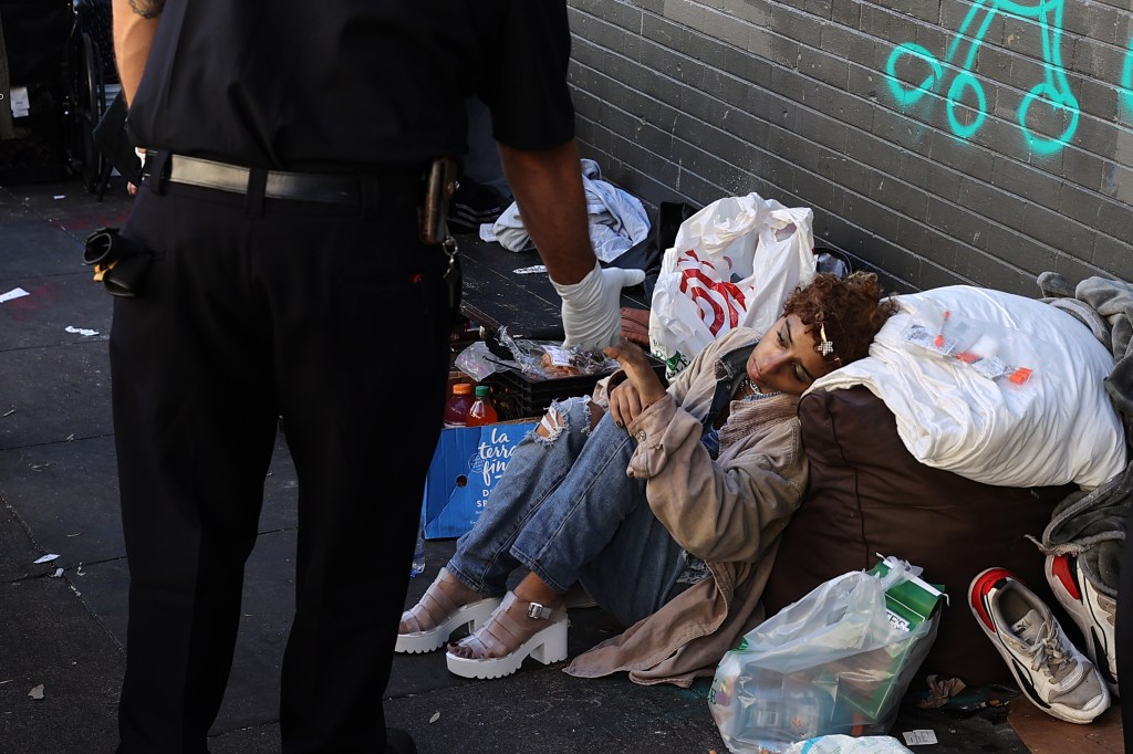 A paramedic offers help to a homeless woman sleeping in the Tenderloin district of San Francisco on Oct. 9, 2022.