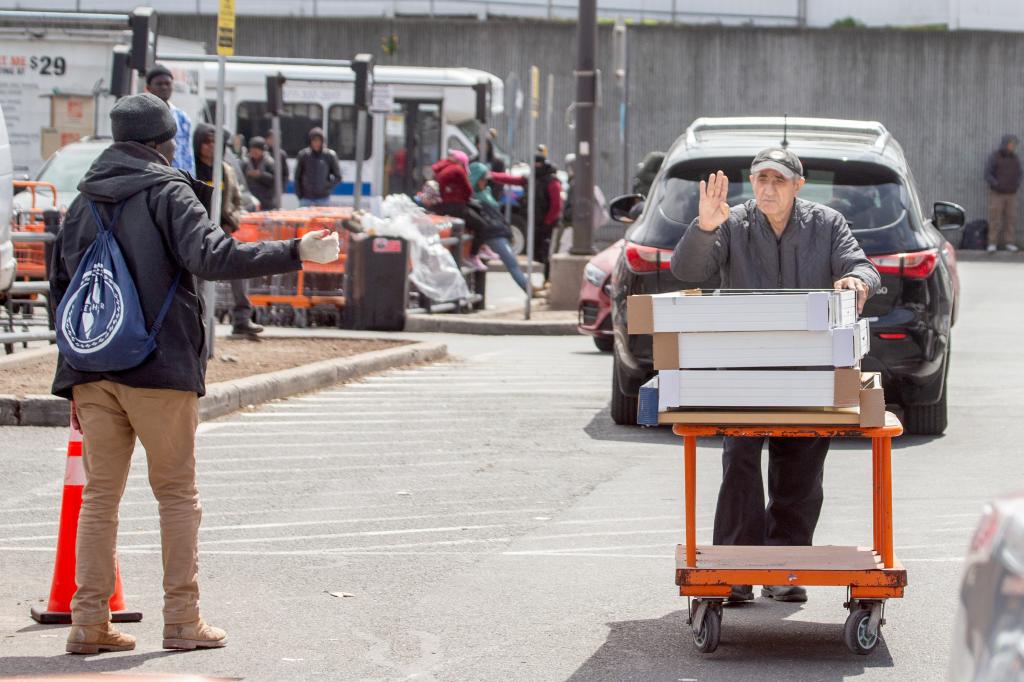 migrant approaches customer leaving Home Depot with his purchases while the customer puts up his hand to indicate he didn't want help