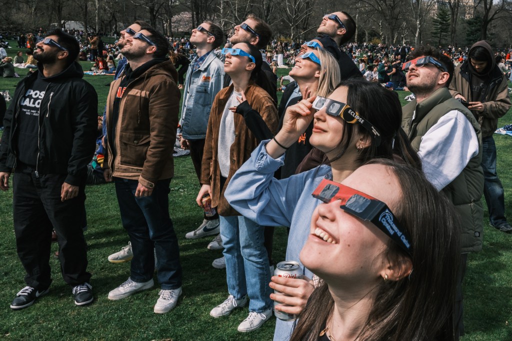 People gather at the Sheepâs Meadow in Central Park in Manhattan to watch the solar eclipse. 