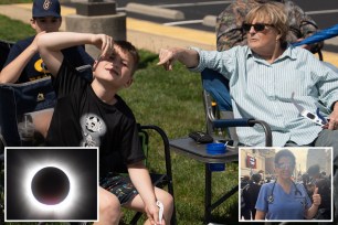 People gathered at Sheep's Meadow in Central Park, Manhattan to watch the solar eclipse on April 5, 2024, including a woman and a boy sitting in chairs.