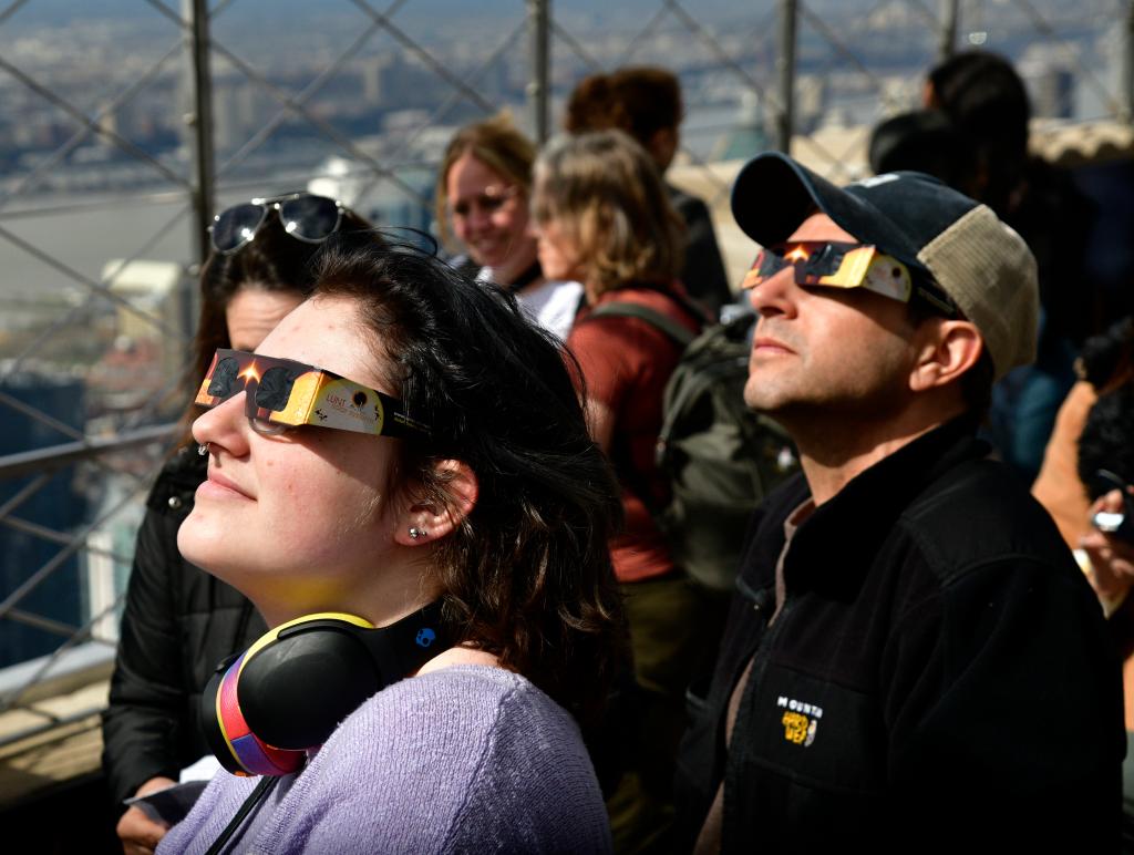 People gather to view the solar eclipse at the Empire State Building on Monday.