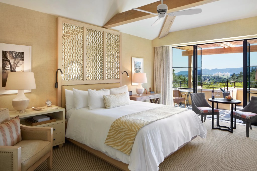 A bedroom with a large bed and a balcony overlooking the beautiful views of the Napa Valley at Auberge du Soleil