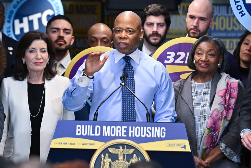 NYC Mayor Eric Adams delivering remarks at NYS Governor Hochul's housing announcement event, alongside notable figures like Kathy Hochul and Andrea Stewart-Cousins.