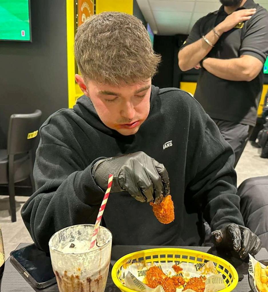 Ollie Leonard trying the 15 chicken wings coated in a Carolina Reaper sauce challenge at Wing Kingz in Canterbury. Kent.