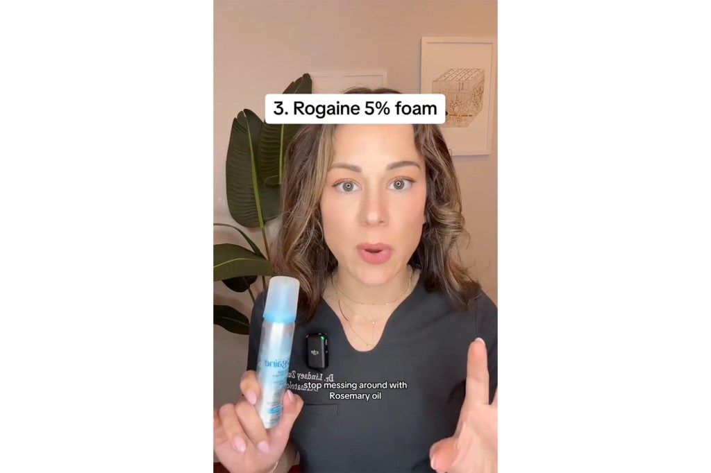 A woman holding a Rogaine spray bottle