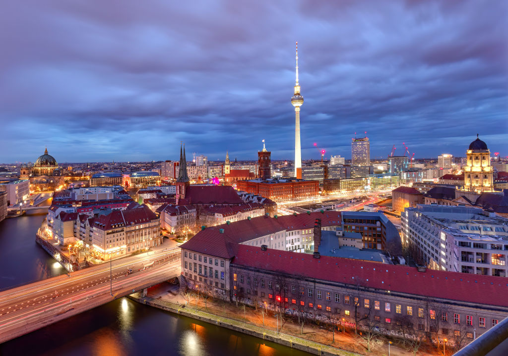 Fireworks illuminating the skyline of Berlin on New Year's Eve, featuring landmarks such as the TV tower, red town hall, and the dome of the Berlin Cathedral.