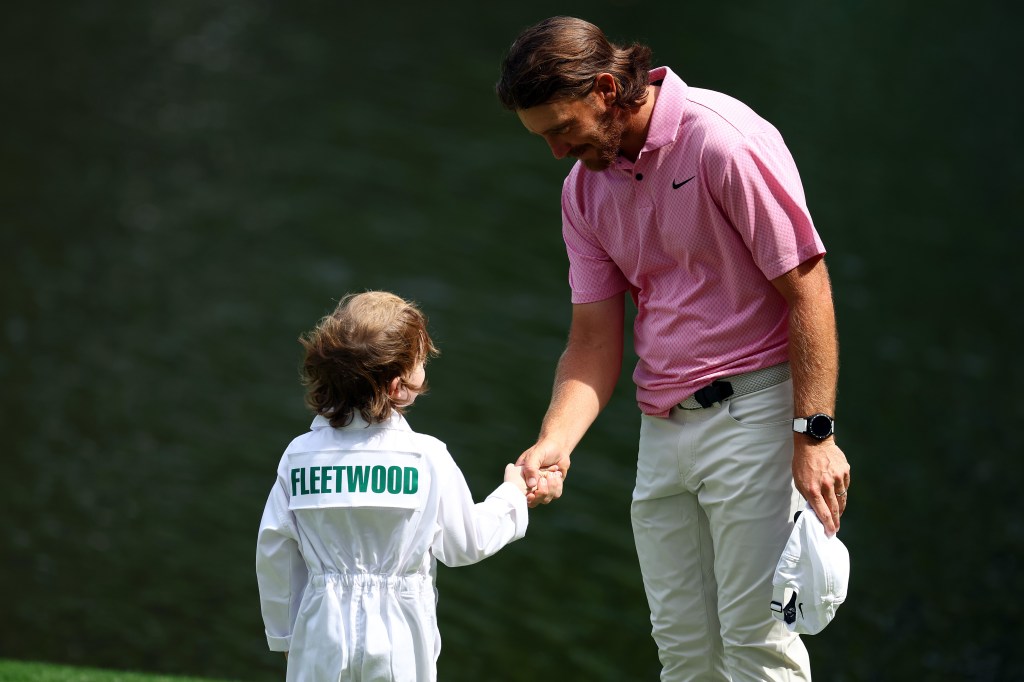 Tommy Fleetwood of England shakes hands with son, Franklin, on the ninth green during the Par Three Contest