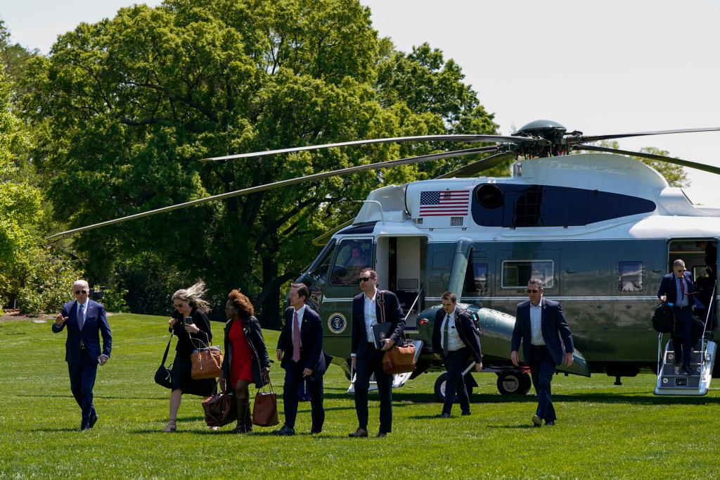 Staff wait to walk with US President Joe Biden (L) from Marine One to the residence of the White House in Washington, DC, on April 26, 2024.