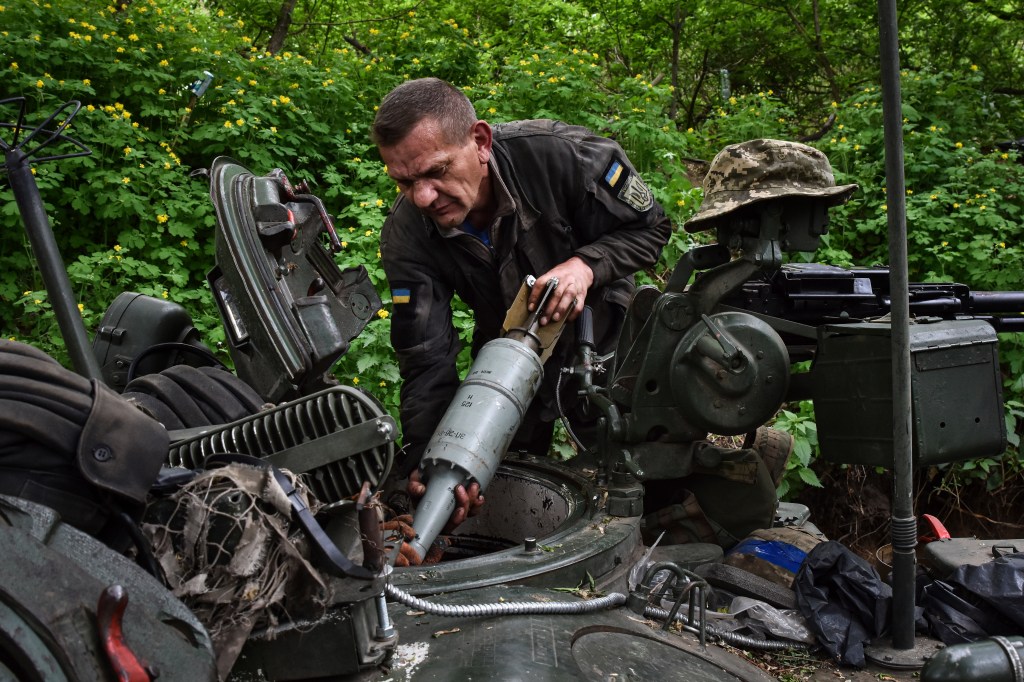 A Ukrainian serviceman of 65th brigade loads shells into a tank. 