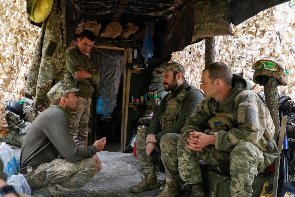 Ukrainian servicemen speak to each other next to a dugout at their position in a front line near the town of Kreminna, amid Russia's attack on Ukraine.