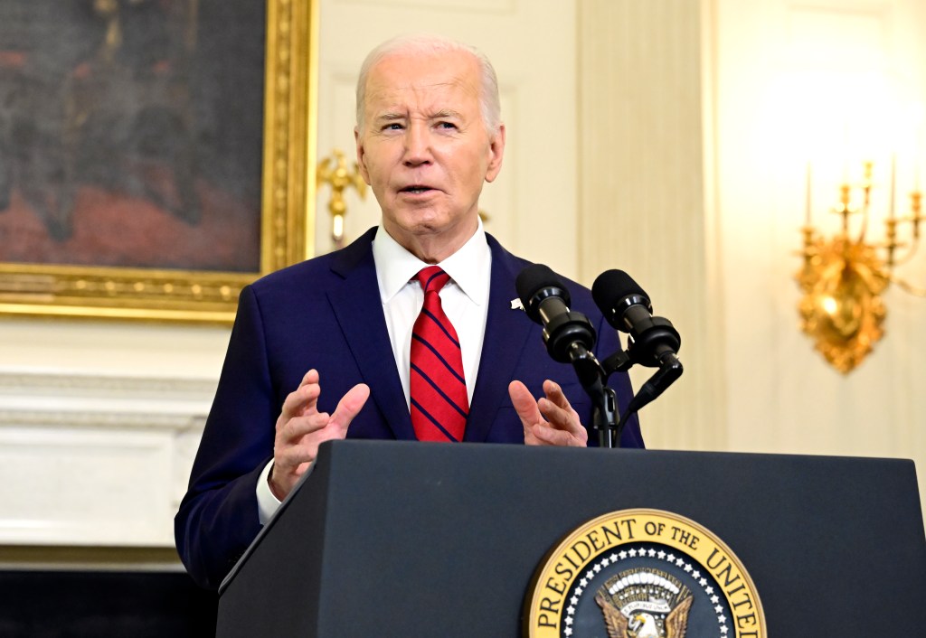 President Joe Biden speaking into microphones after signing the $95 billion National Security Package in the State Dining Room of the White House
