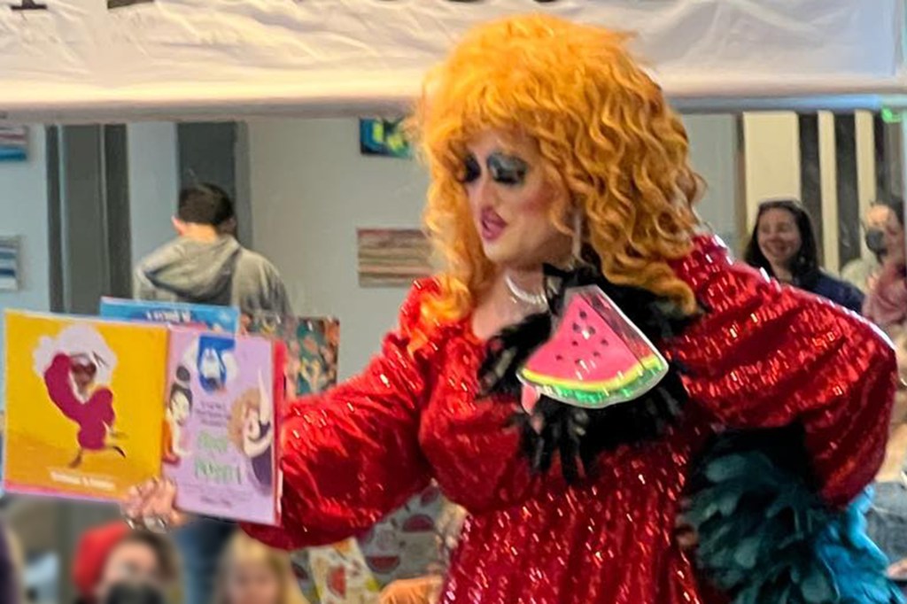 Drag Queen wearing a watermelon pin reading a book to chilldren