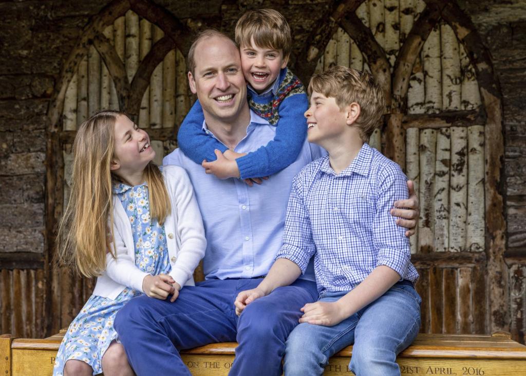 Prince William sitting with his children, Princess Charlotte, Prince Louis, and Prince George on a bench, in an official Kensington Palace photo from June 2023