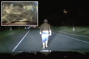 Man jumping on the bonnet of a car and smashing the windscreen at night in a suburban street