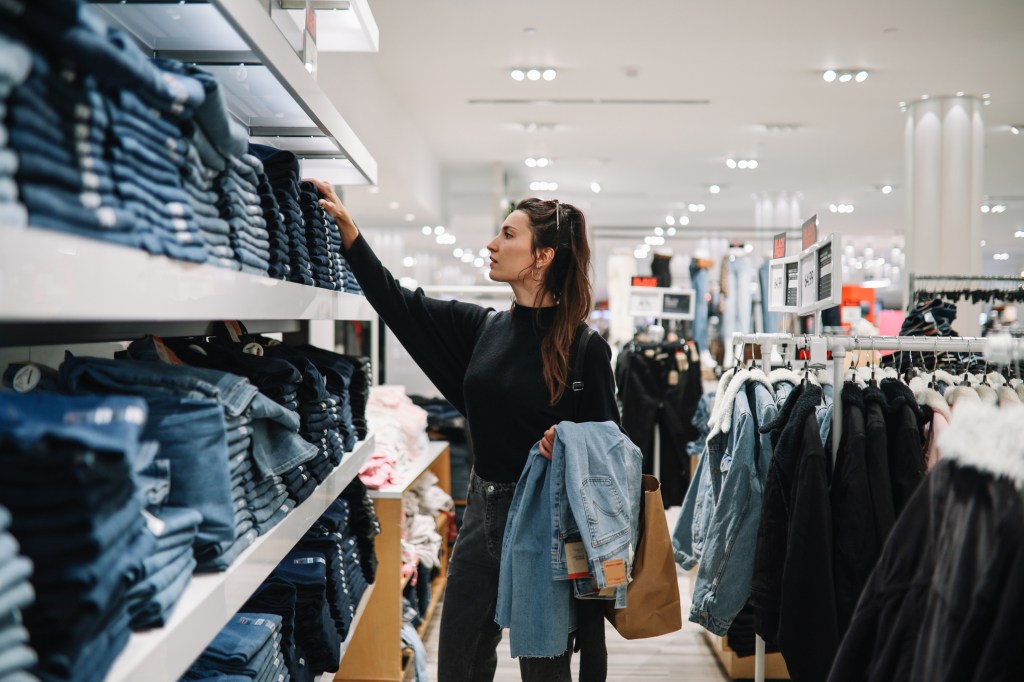 Woman in mid 30s goes shopping for denim jeans.