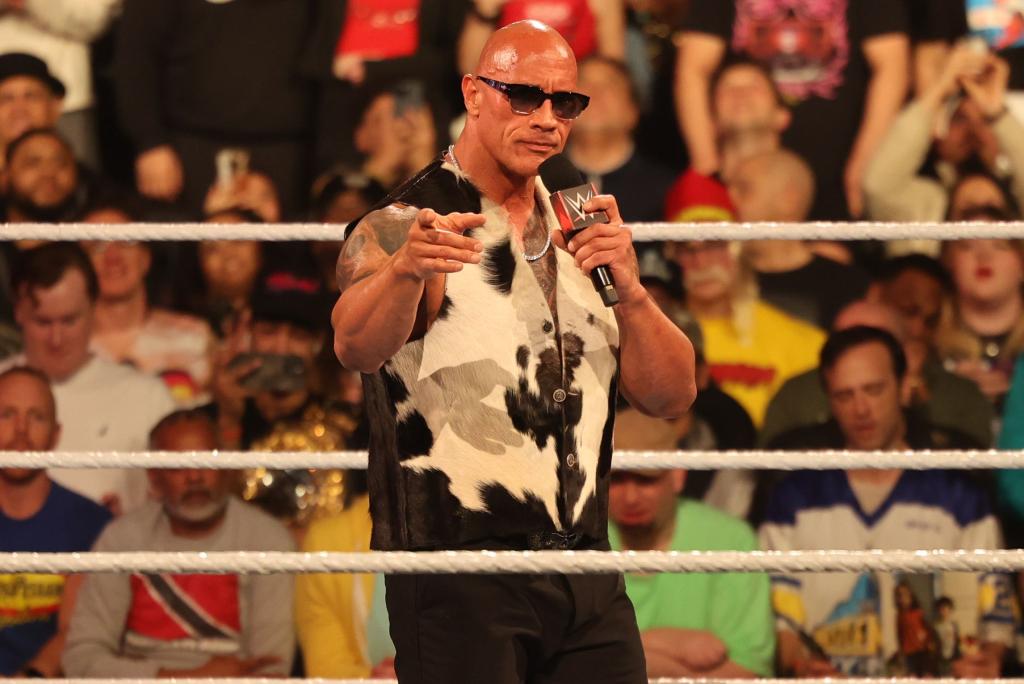 Dwayne 'The Rock' Johnson, wearing a cow print shirt, speaks into a microphone at WWE Monday Night Raw in Barclays Center, New York, 2024