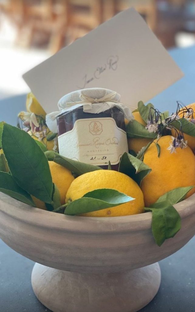 A bowl of fruit next to a jar of strawberry jam