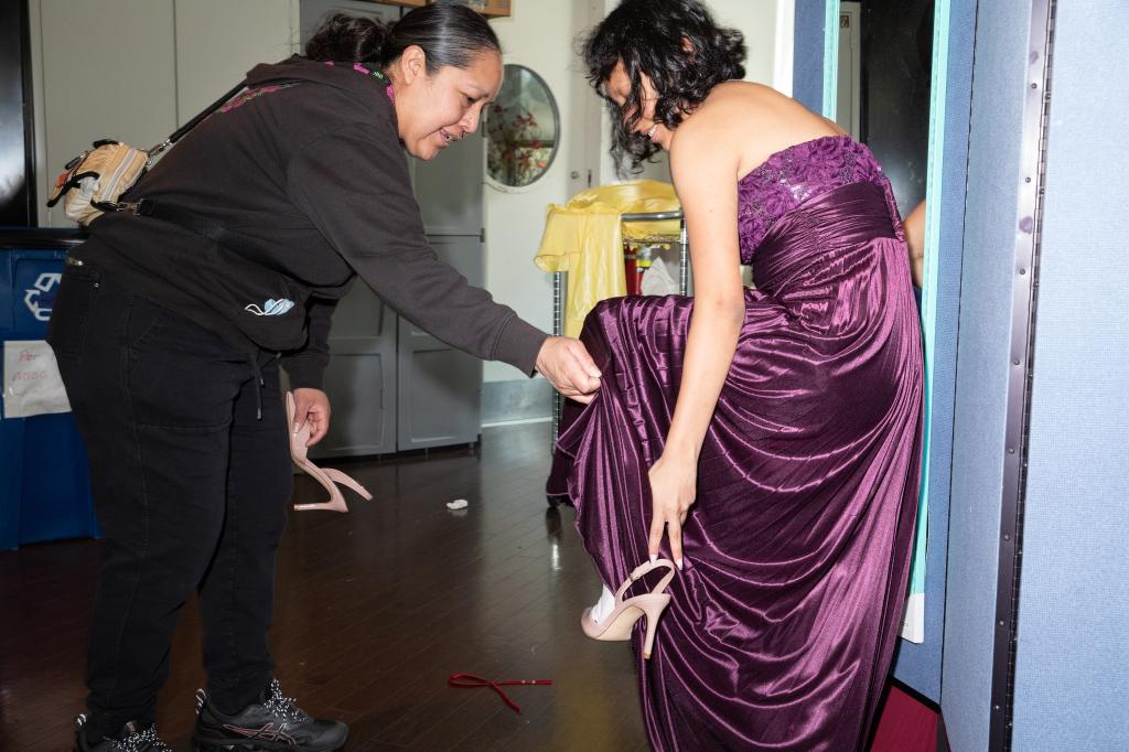 Xoshitl Ortigoza helping her daughter Rose Ortigoza put on heels in a makeshift dressing room at a prom clothing giveaway event