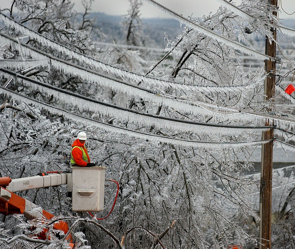 Tree service worker, Jose L. Gallardo, removing a tree branch from power lines in winter conditions in McAlester, Oklahoma after a severe ice storm