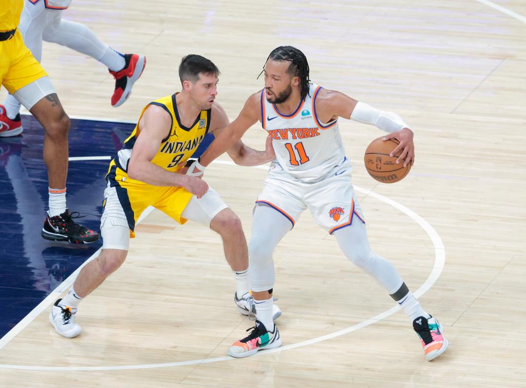 Jalen Brunson #11 of the New York Knicks driving down the court with a basketball, defended by T.J. McConnell #9 of the Indiana Pacers during an NBA Playoffs game.