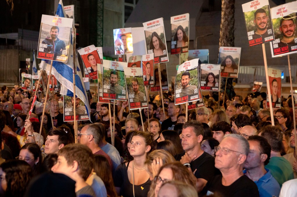 Israelis holding signs with pictures of hostages taken by Hamas at a "United We Bring Them Home" rally in Tel Aviv on May 18, 2024.