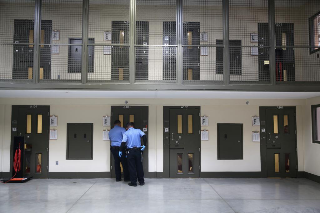 Guards prepare to escort an immigrant detainee from his 'segregation cell' back into the general population at the Adelanto Detention Facility.