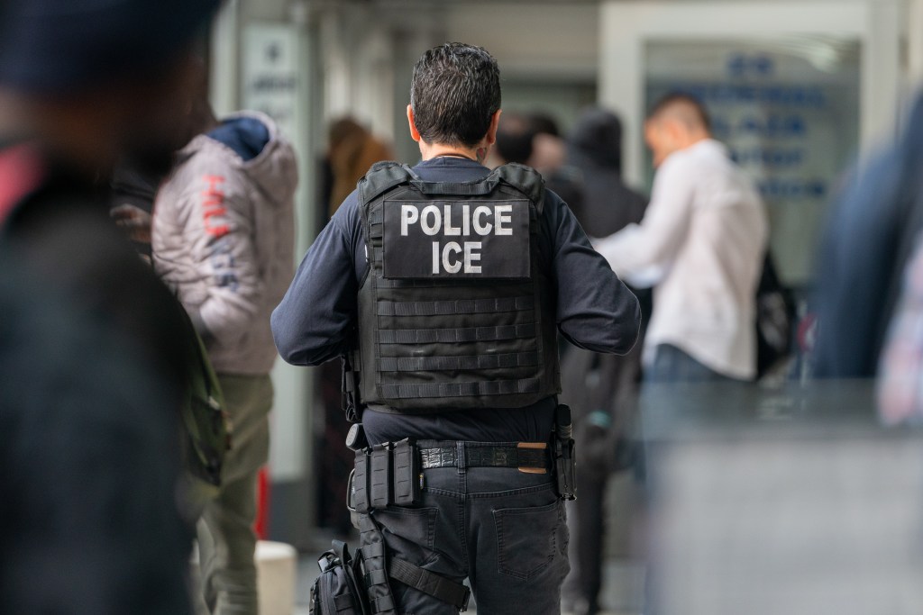 An ICE agent monitors migrants in New York City