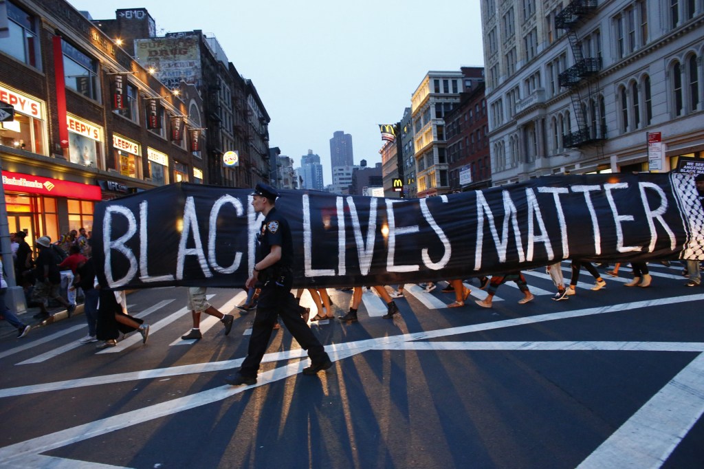 Protesters carrying a "Black Lives Matter" banner across a street